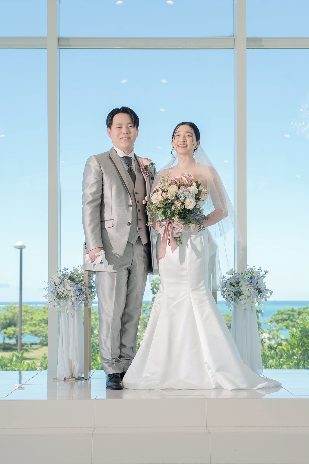 大きな窓のあるチャペルで並ぶ新郎新婦