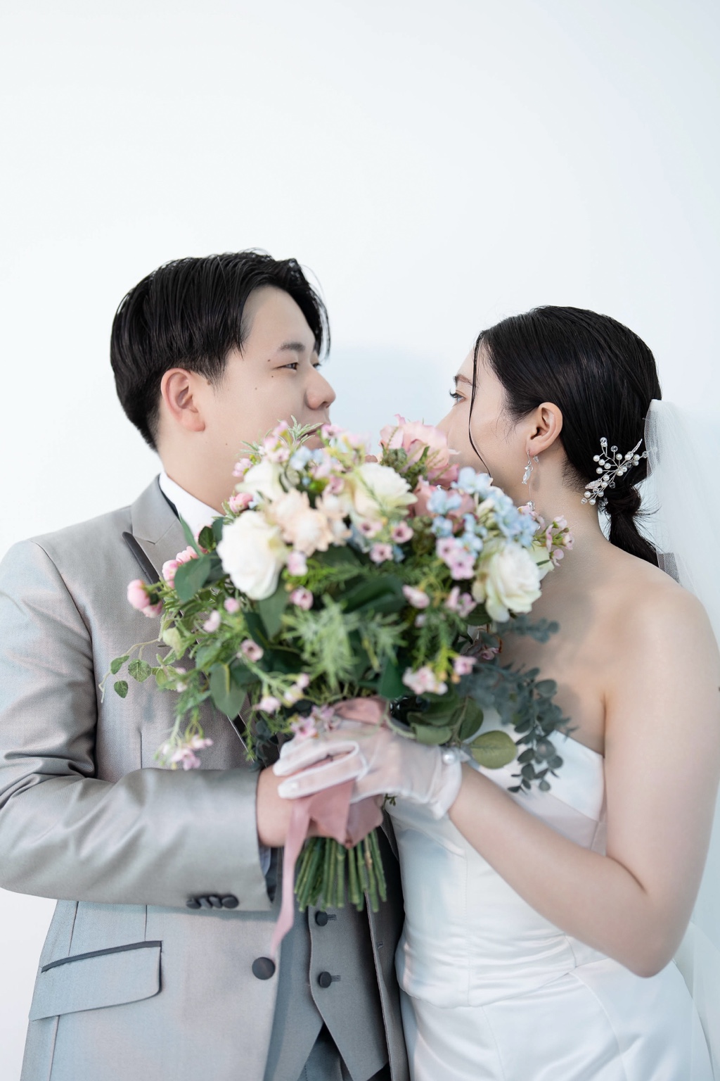 ブーケを間に顔を寄せて見つめ合う新郎新婦