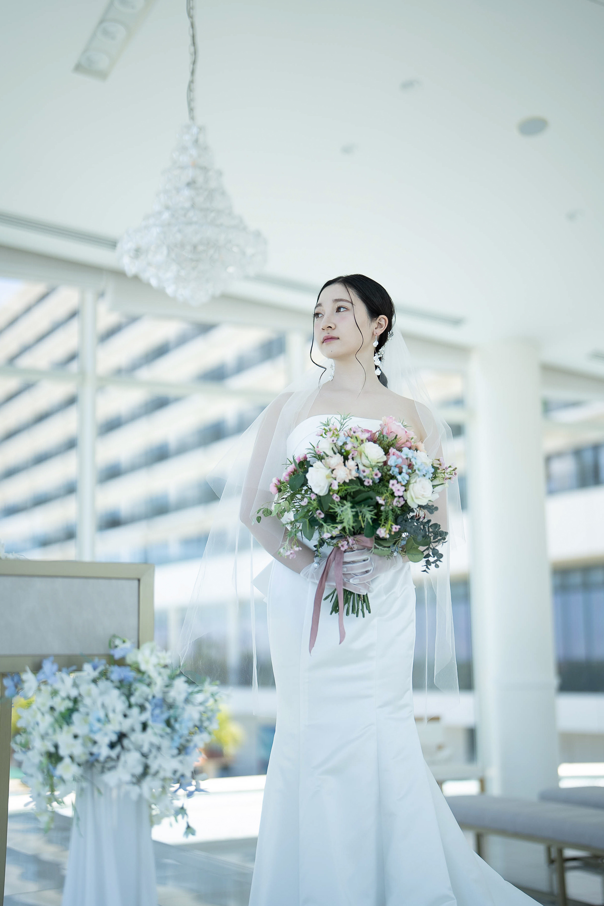 シャンデリアの下でブーケを手に佇む新婦