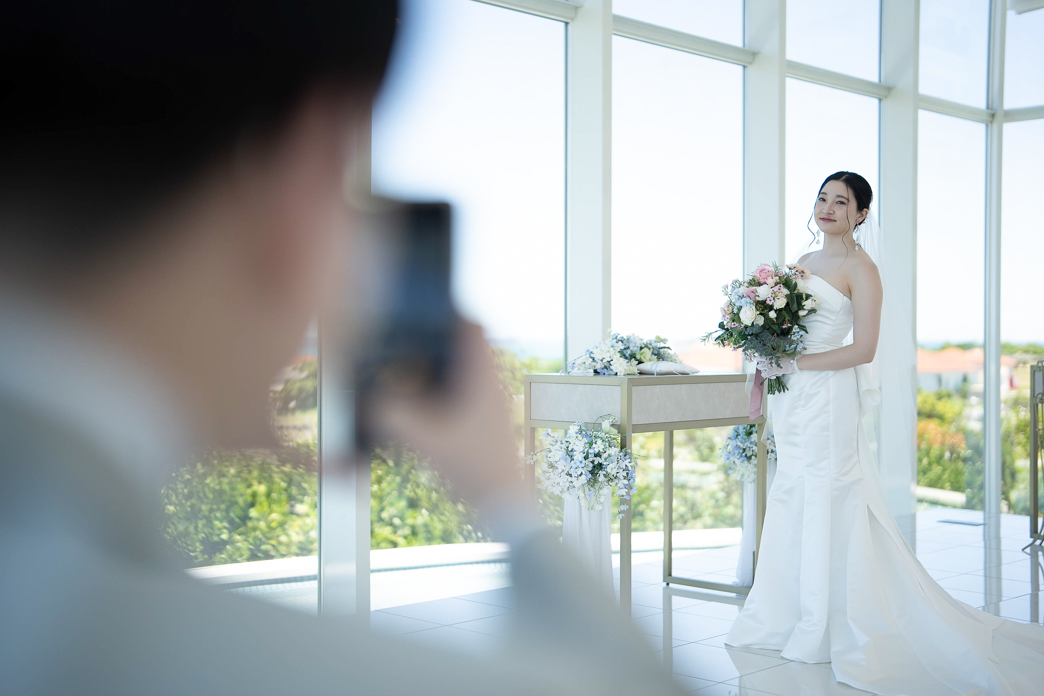 明るいチャペルの窓辺でブーケを持つ新婦