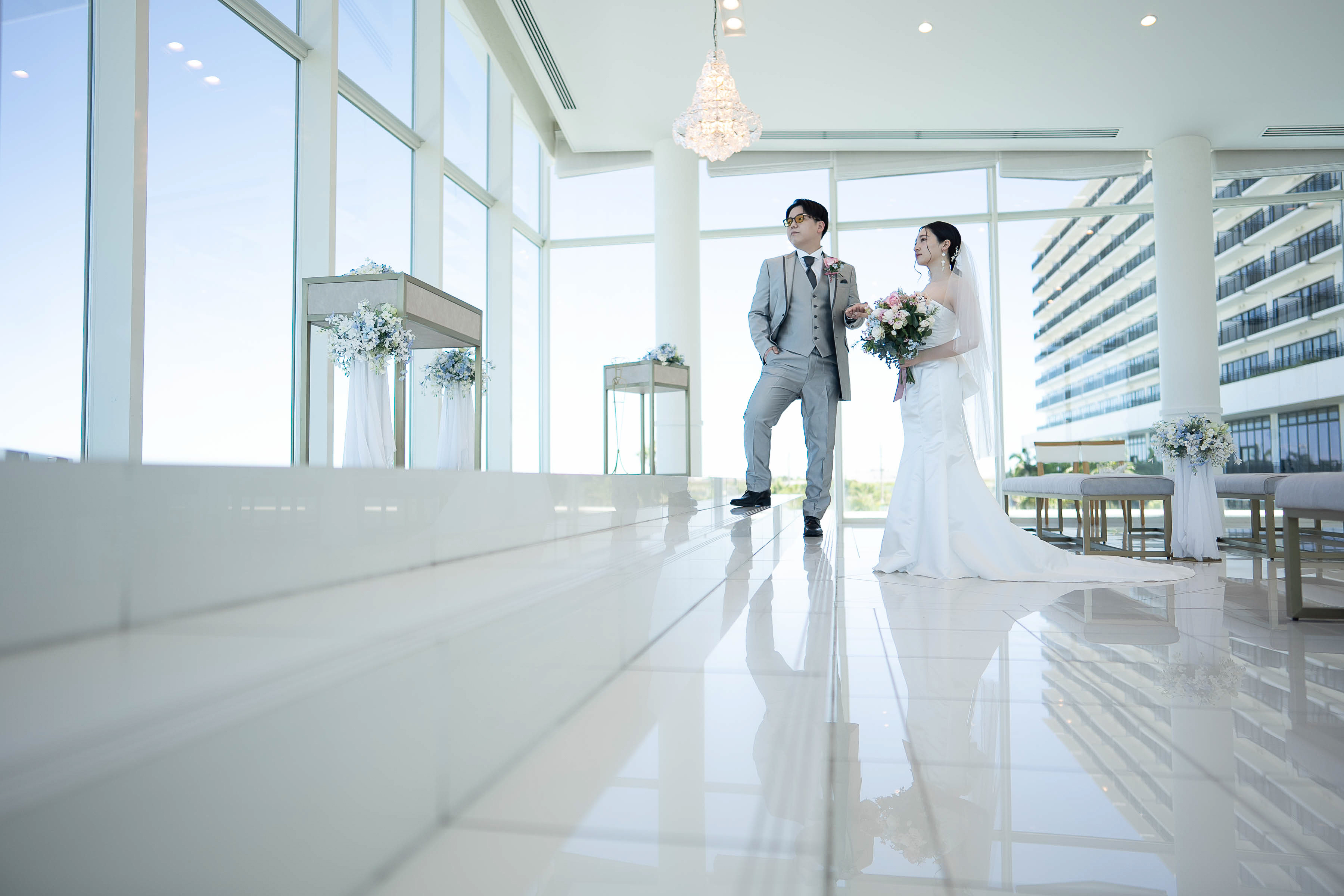 白いチャペルのバージンロードに立つ新郎新婦
